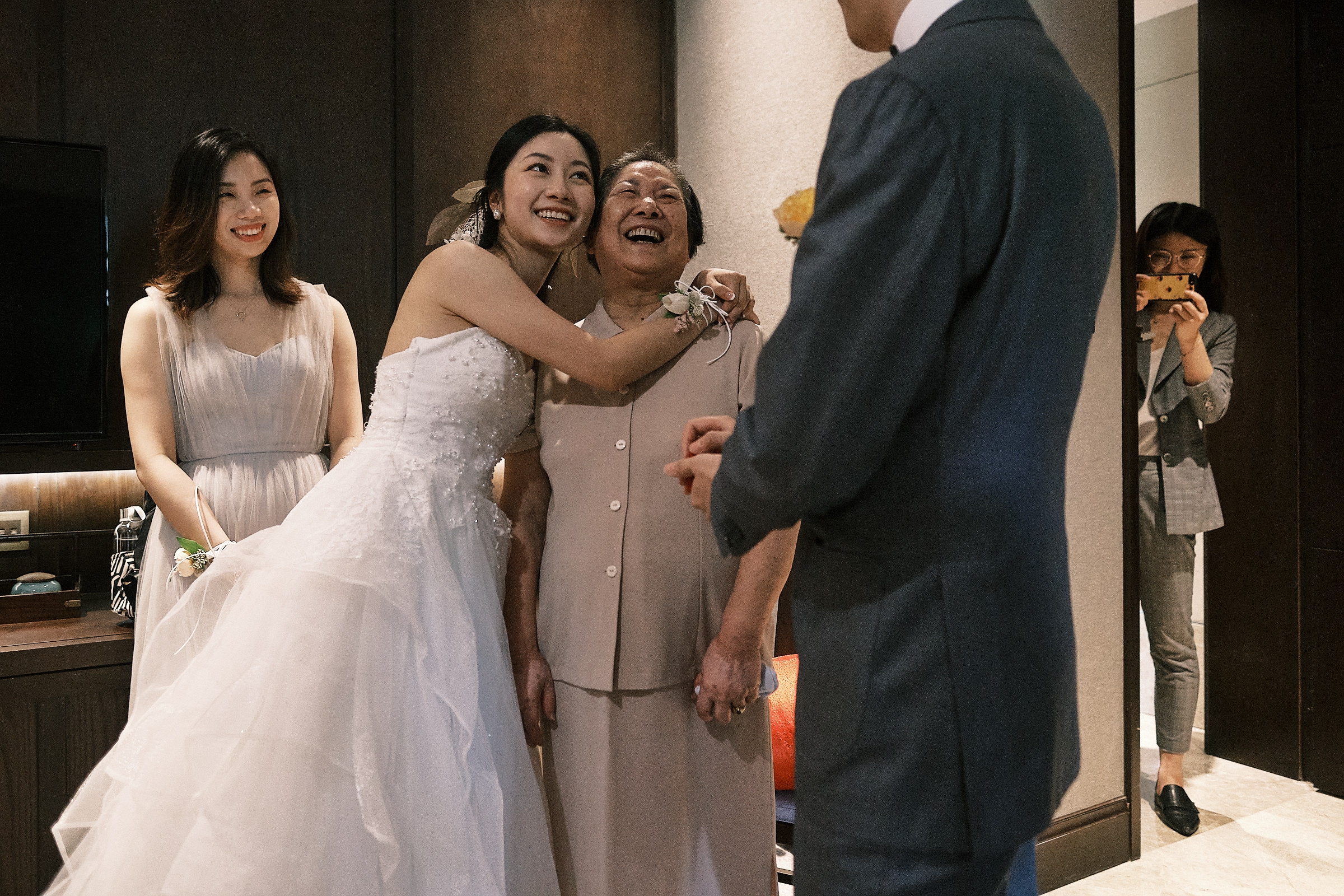 bride embraces grandmother in front of groom bridesmaid and plan