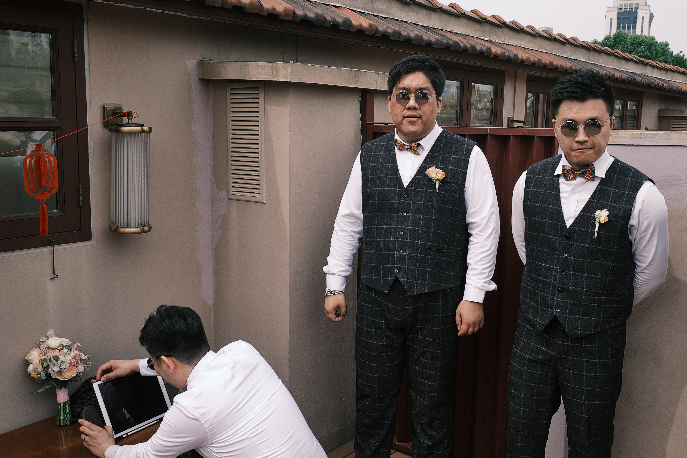 groom prepares his laptop as two groomsmen stand next to him