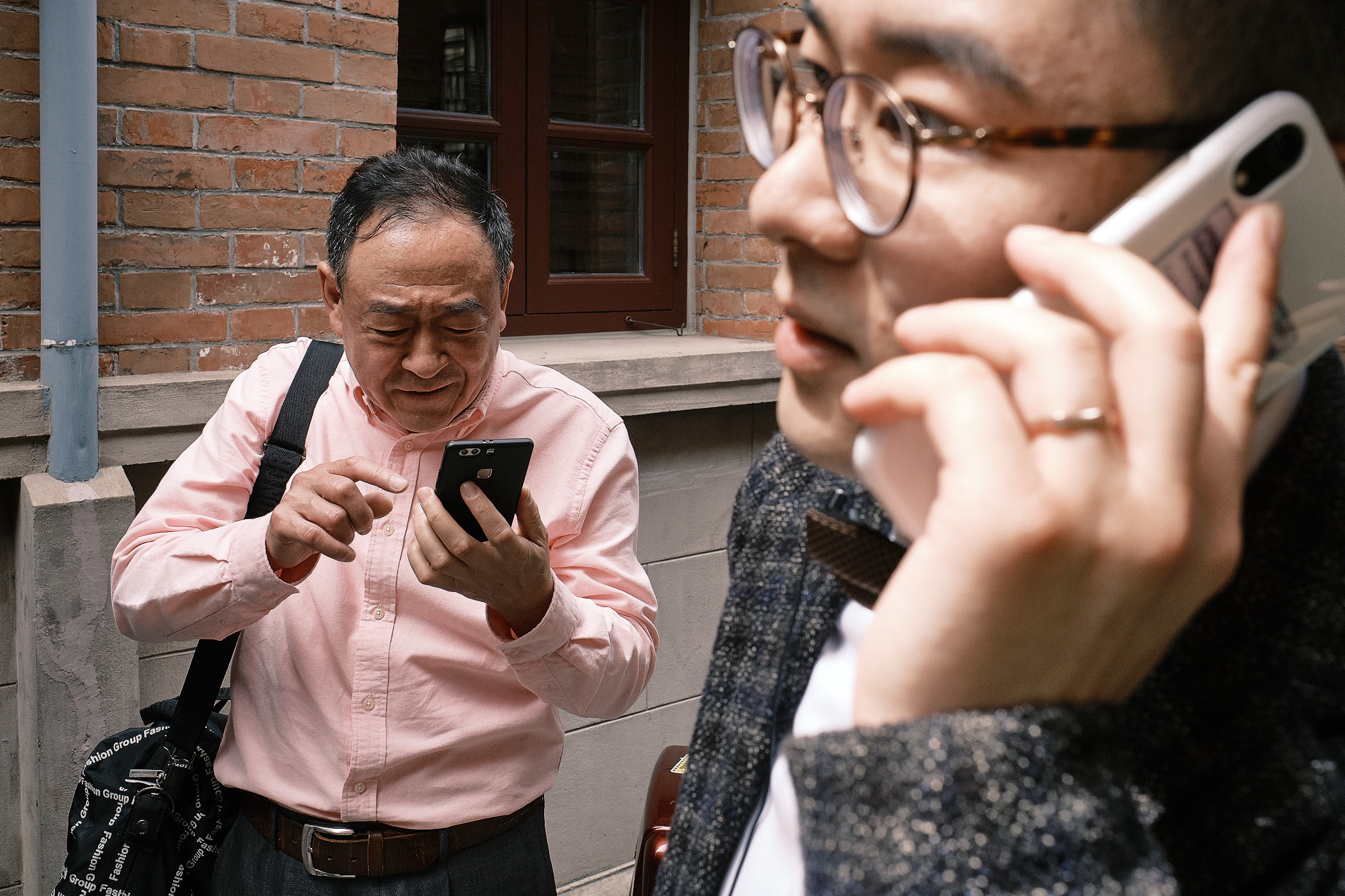 groom talks on the phone while his uncle also has a phone in the hand at a shanghai wedding
