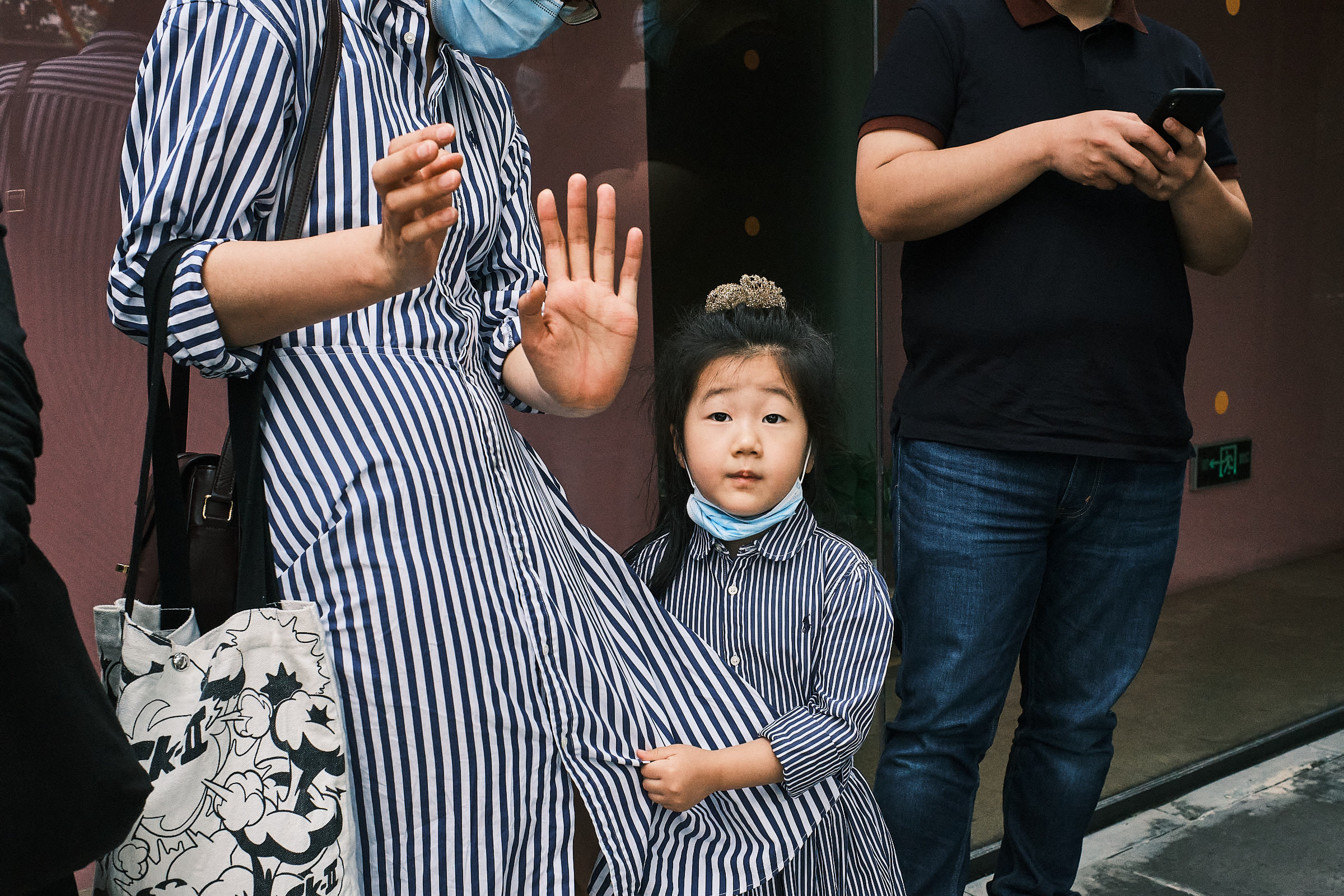 Little Girl Looks At Camera While Her Moms Does Hand Gesture At Wedding In Shanghai