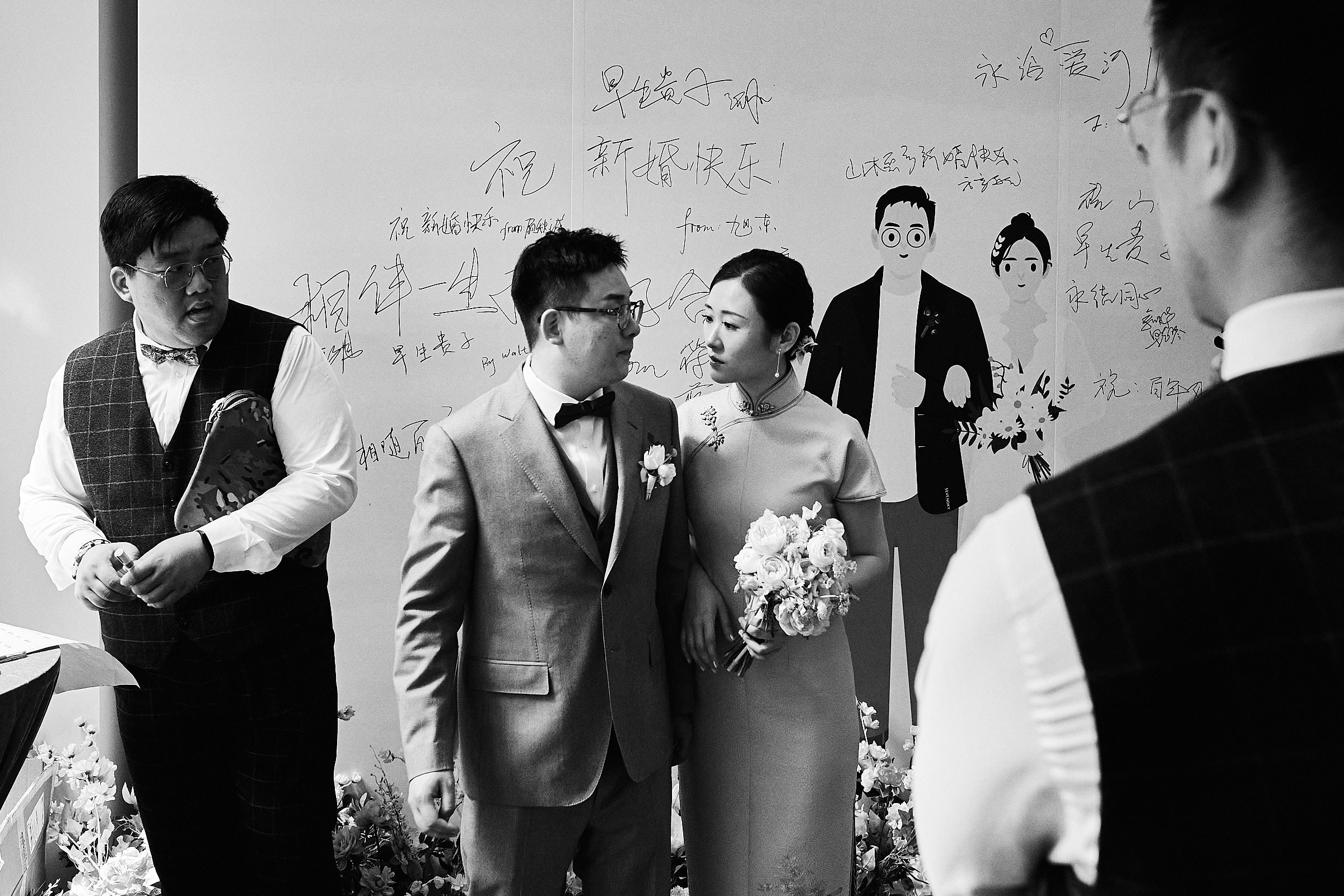 Bride With Groom And Groomsman In Black And White Standing Next To A Big Poster And Drawing Of Them In Their Shanghai Wedding