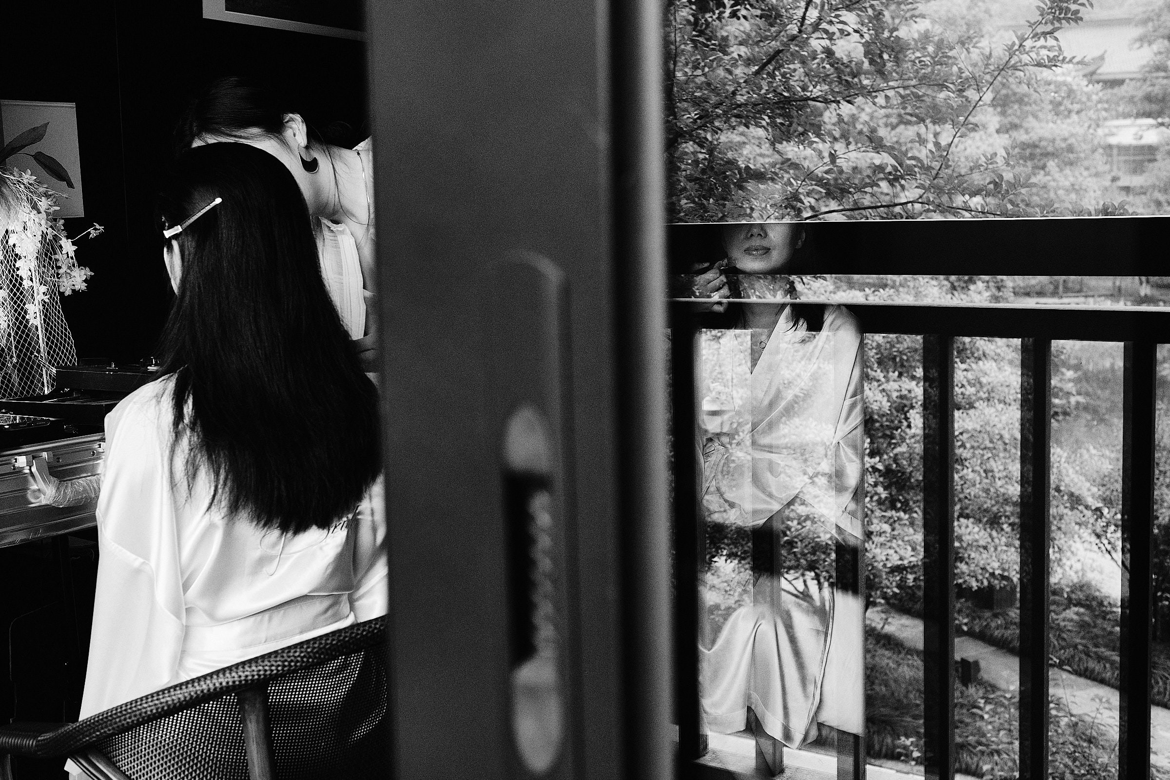 Black And White Image Of Bride And Bridesmaid Doing Makeup With Reflection Of Trees Morning Of Wedding In Hangzhou China