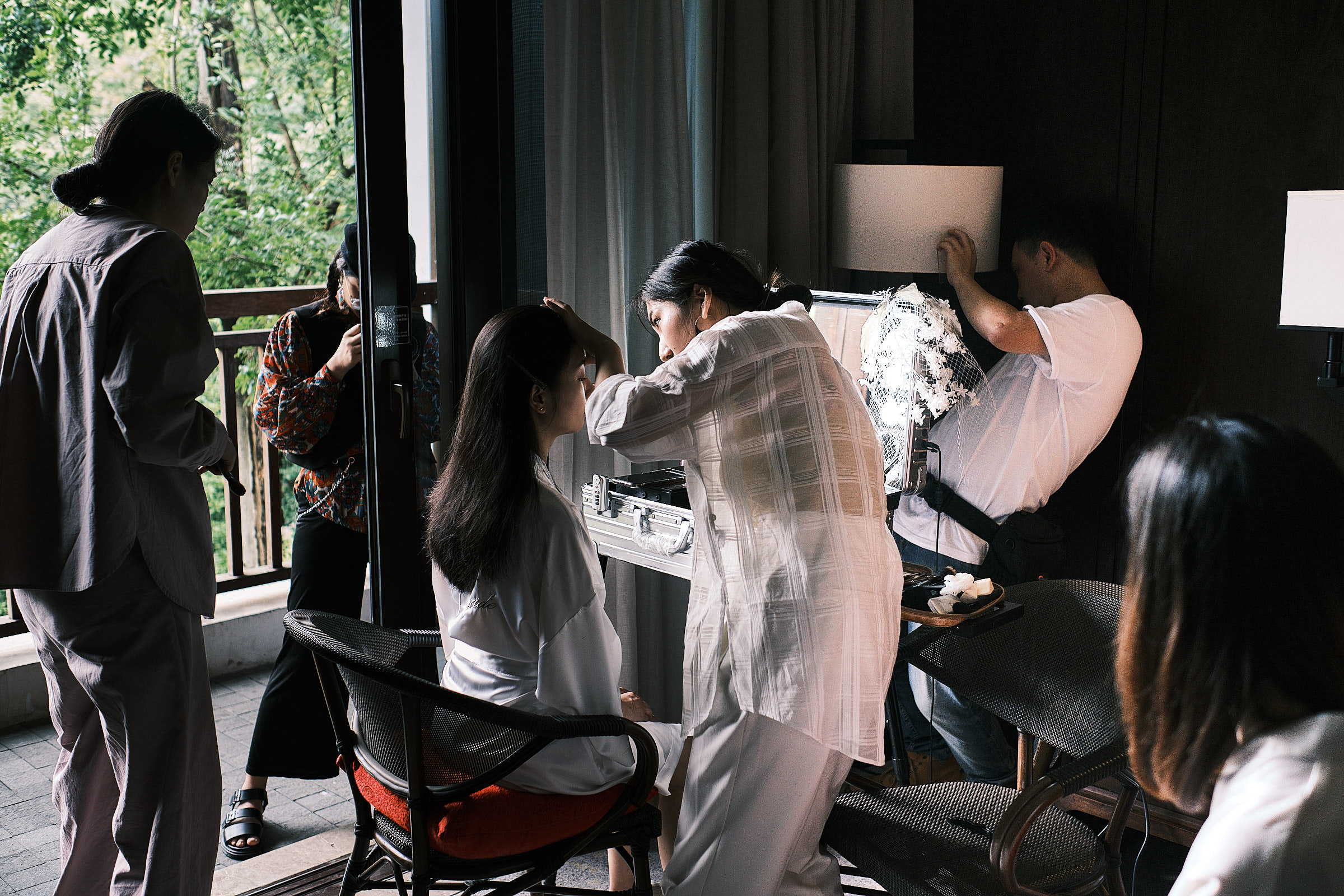 Bride Does Makeup While People Stand Around Her The Morning Of Her Wedding In Hangzhou China