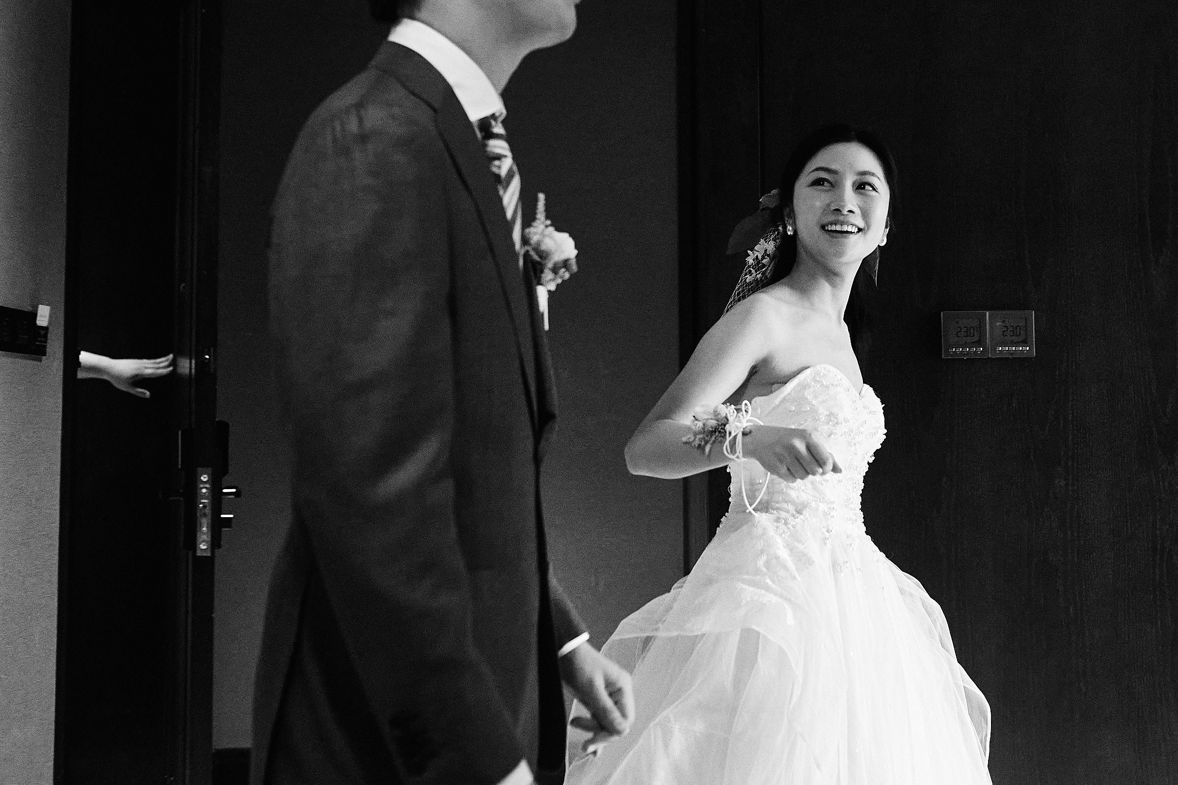Black And White Bride Walks Happily With Groom While A Mystery Hand Holds The Door Open