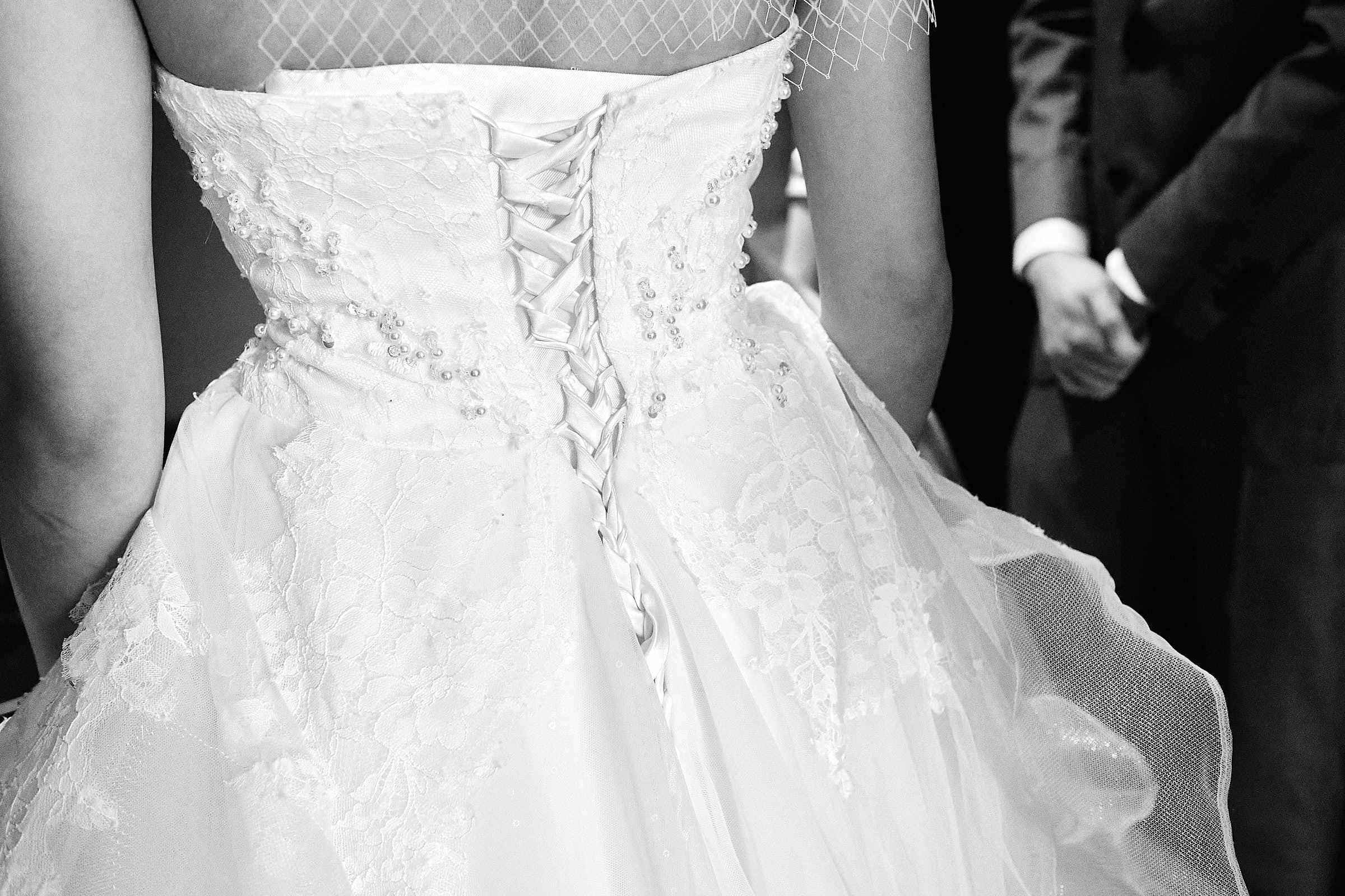 Black And White Closeup Image Of Bridal Dress And Groom Hands