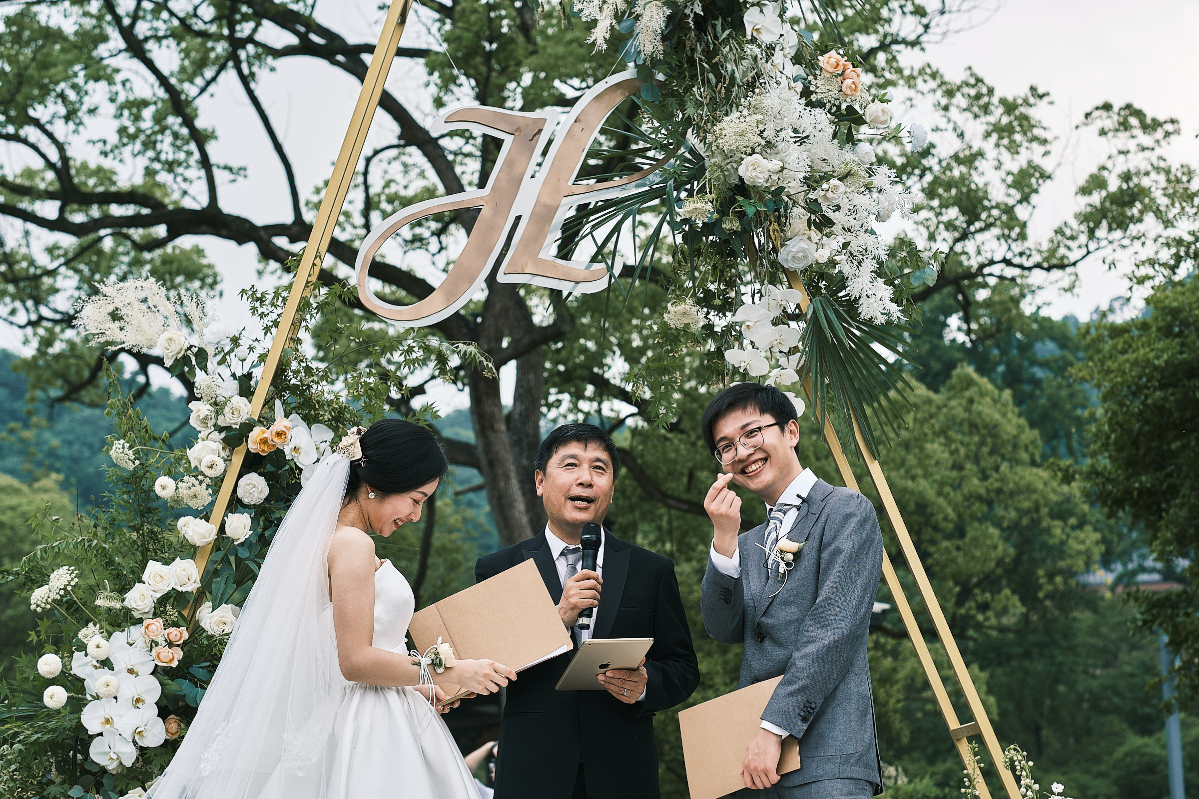 Happy Groom And Bride In The Middle Of Outdoor And Green Ceremony With Officiant