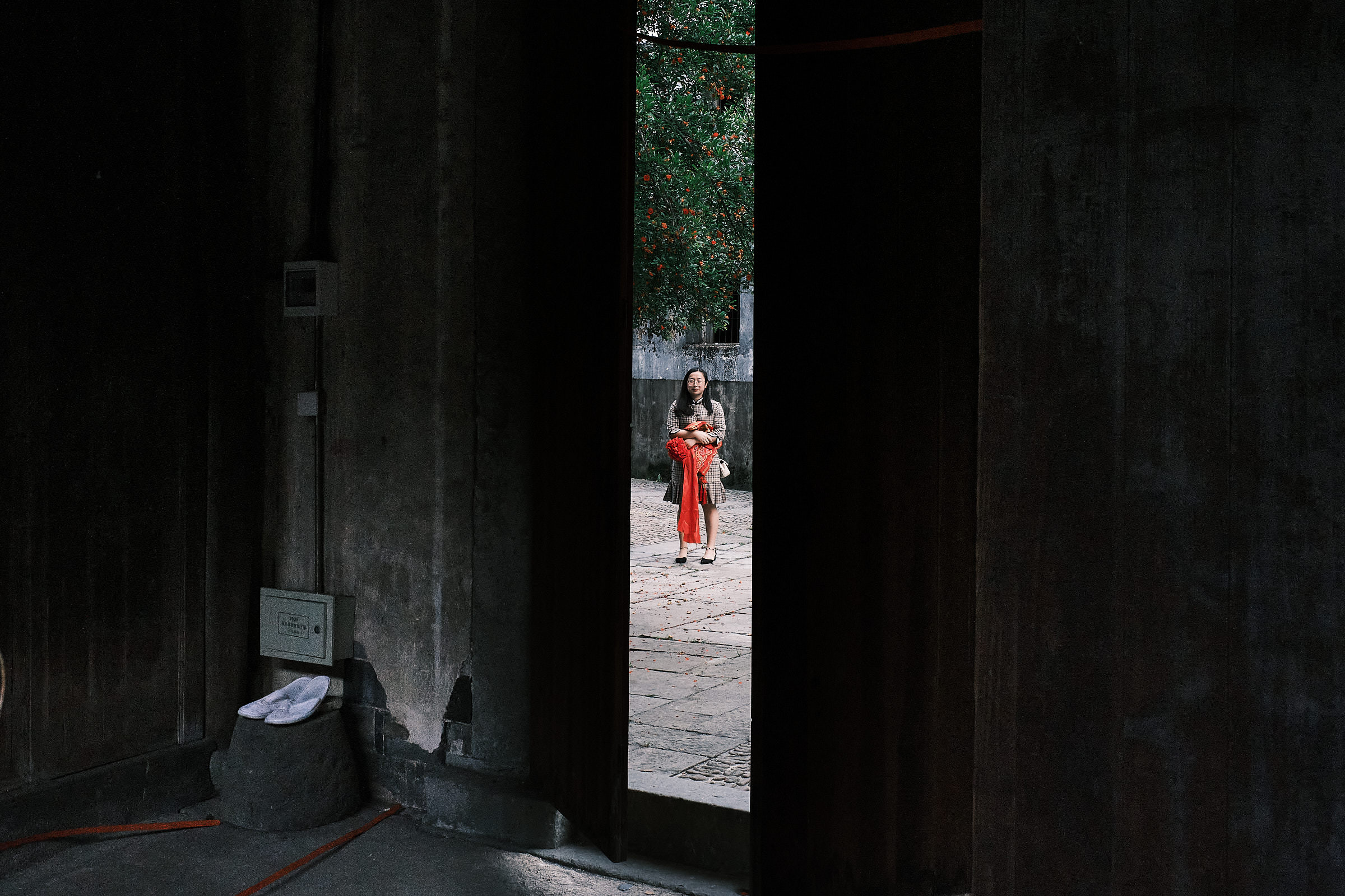 Lady Holding Red Item Is Seen Through The Frame Of A Mystery Door