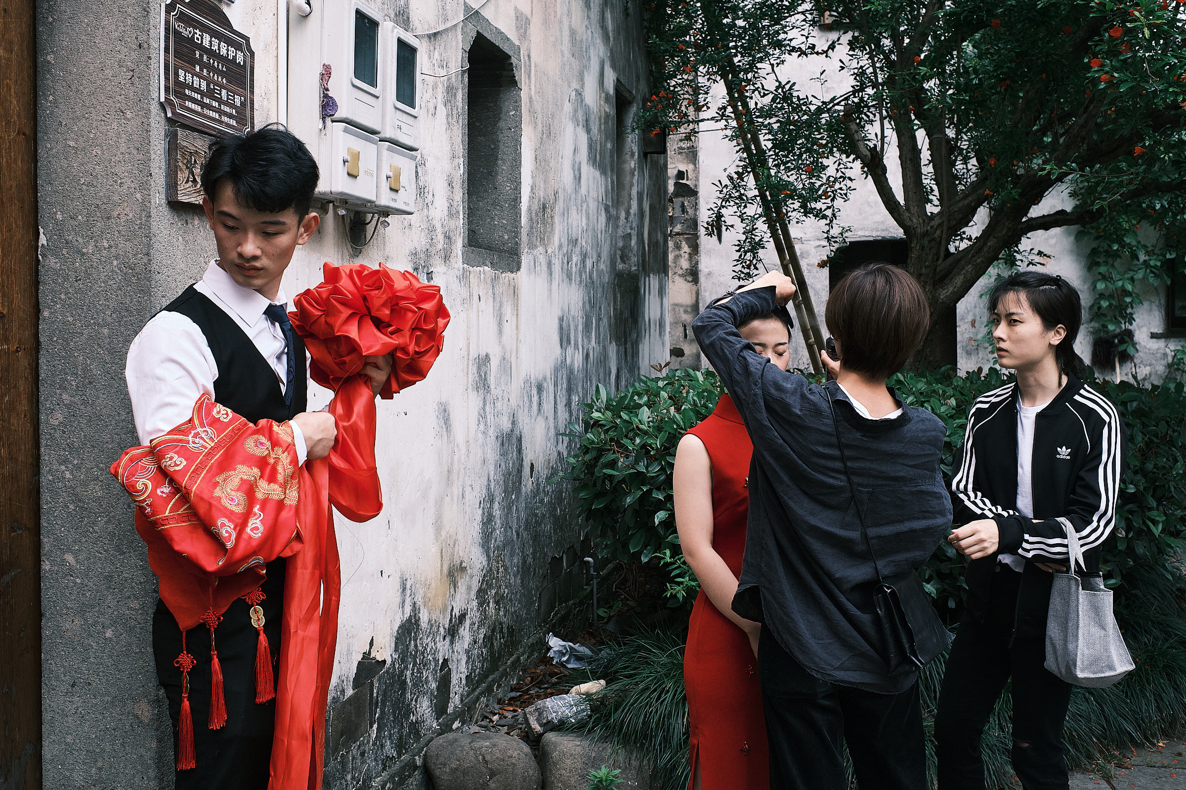 Brother Of The Bride Holds Bow And Red Cover As The Bride Does Final Preparations Before Ceremony