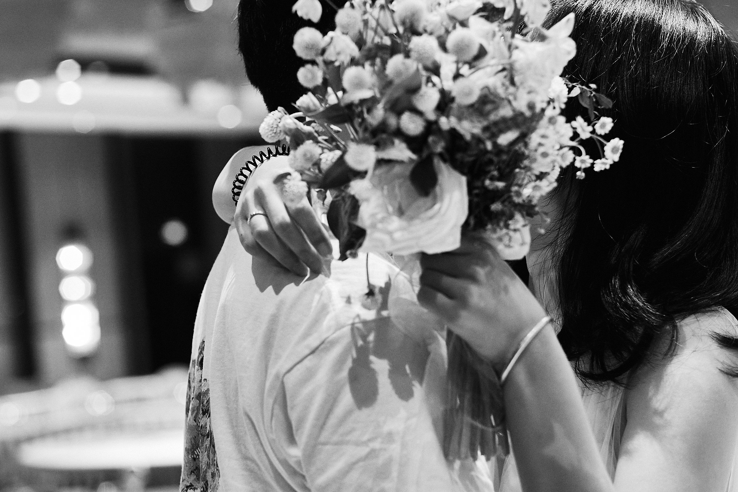 Bride Kisses Groom Behind Flowers