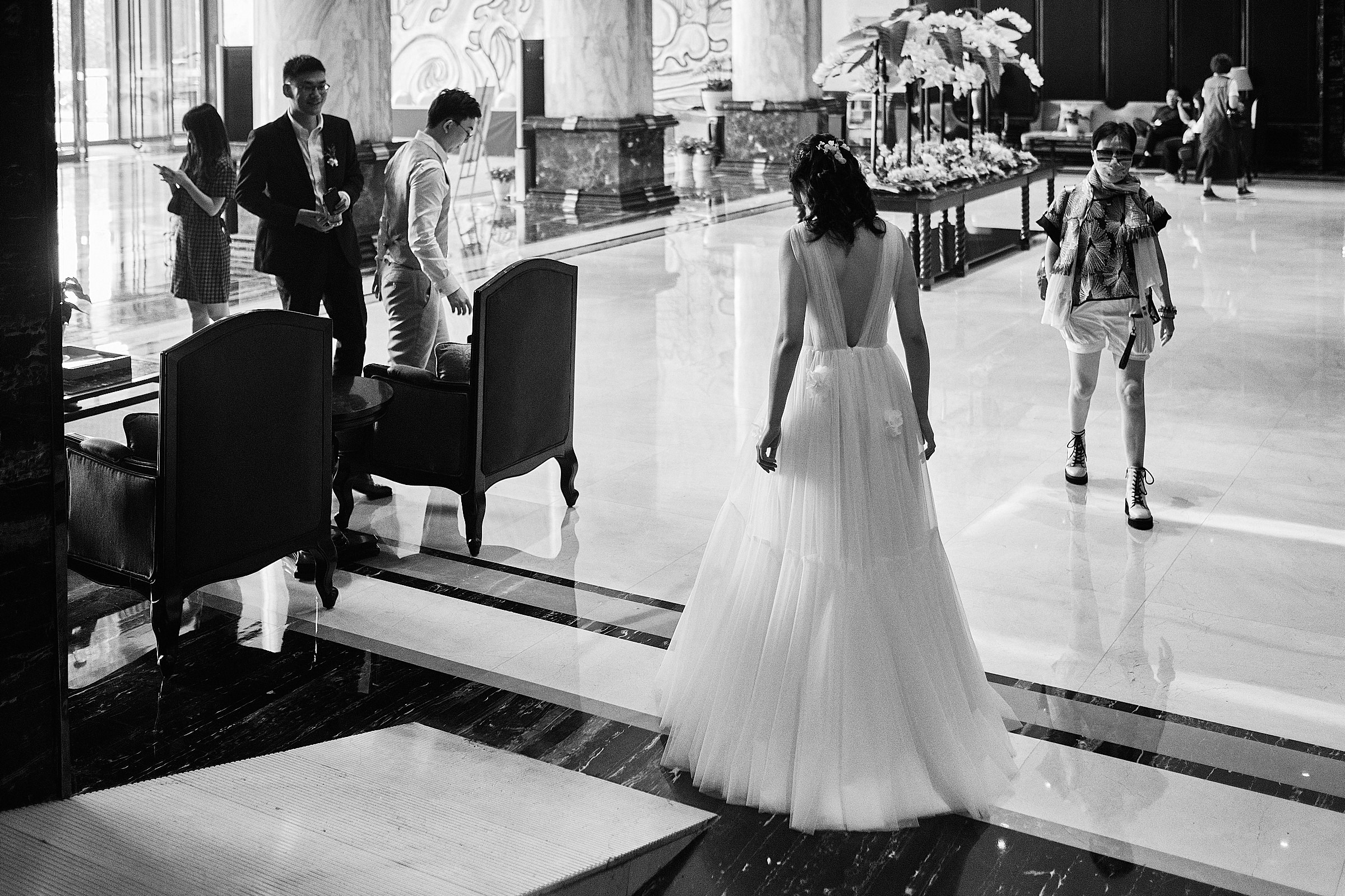 Bride Enters Lobby Of The Wedding Venue In Black And White