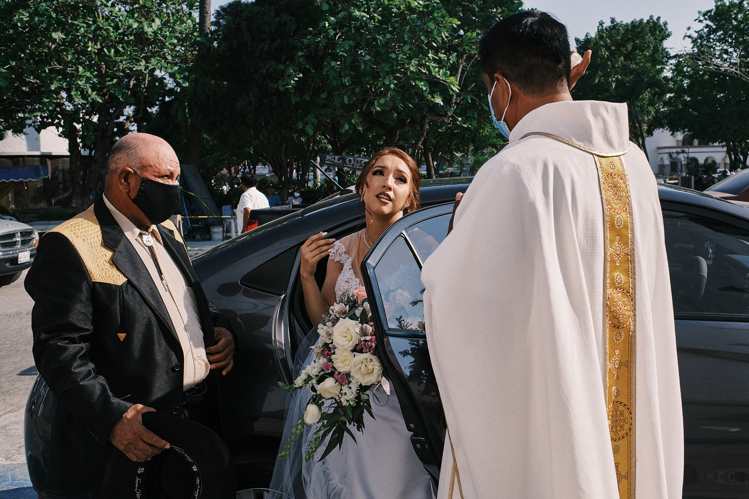 Bride Gets Down Of The Car As The Priest Blesses Her Prior To The Ceremony