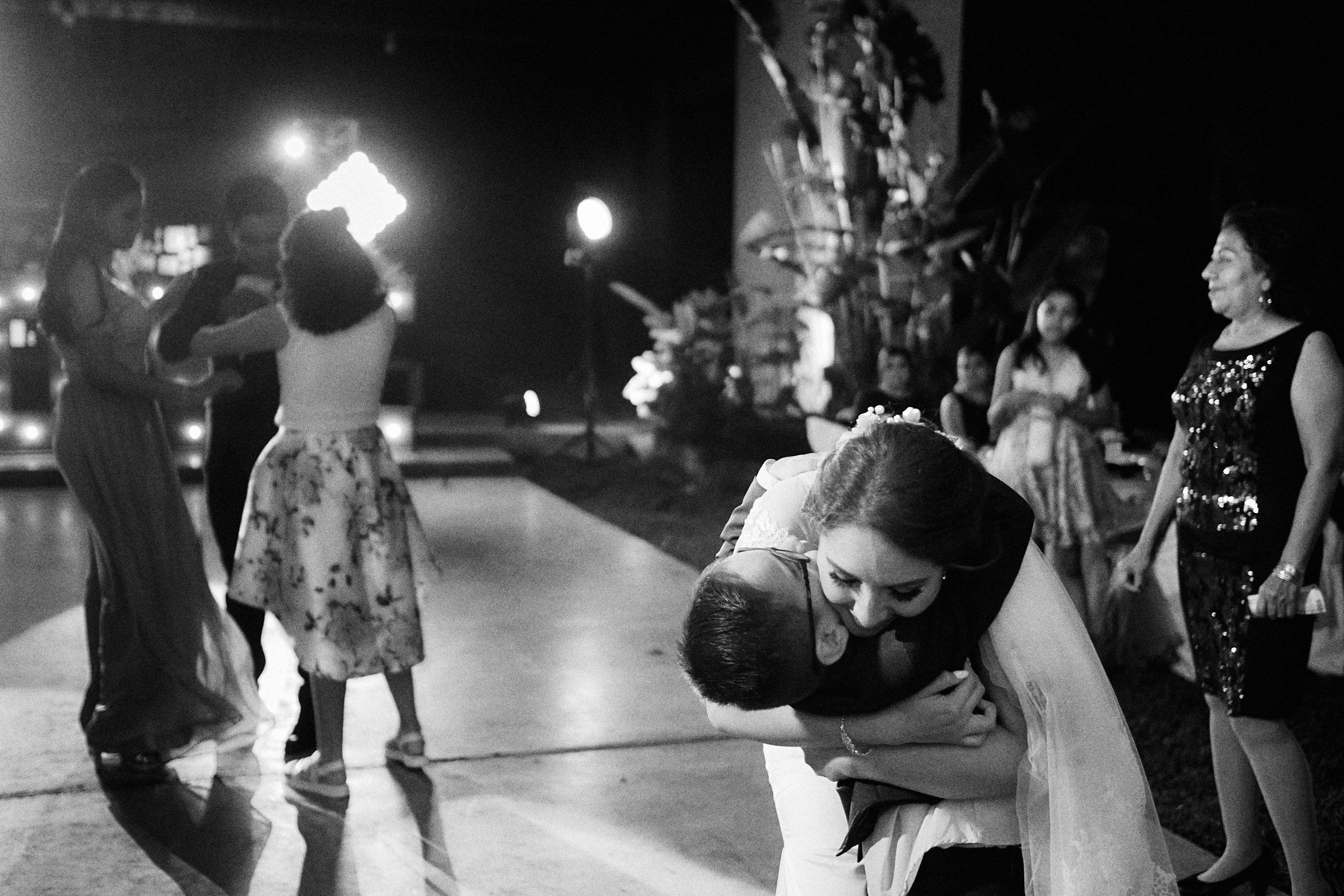 Bride Hugs Young Boy On Dance Floor In Mexico Wedding Reception