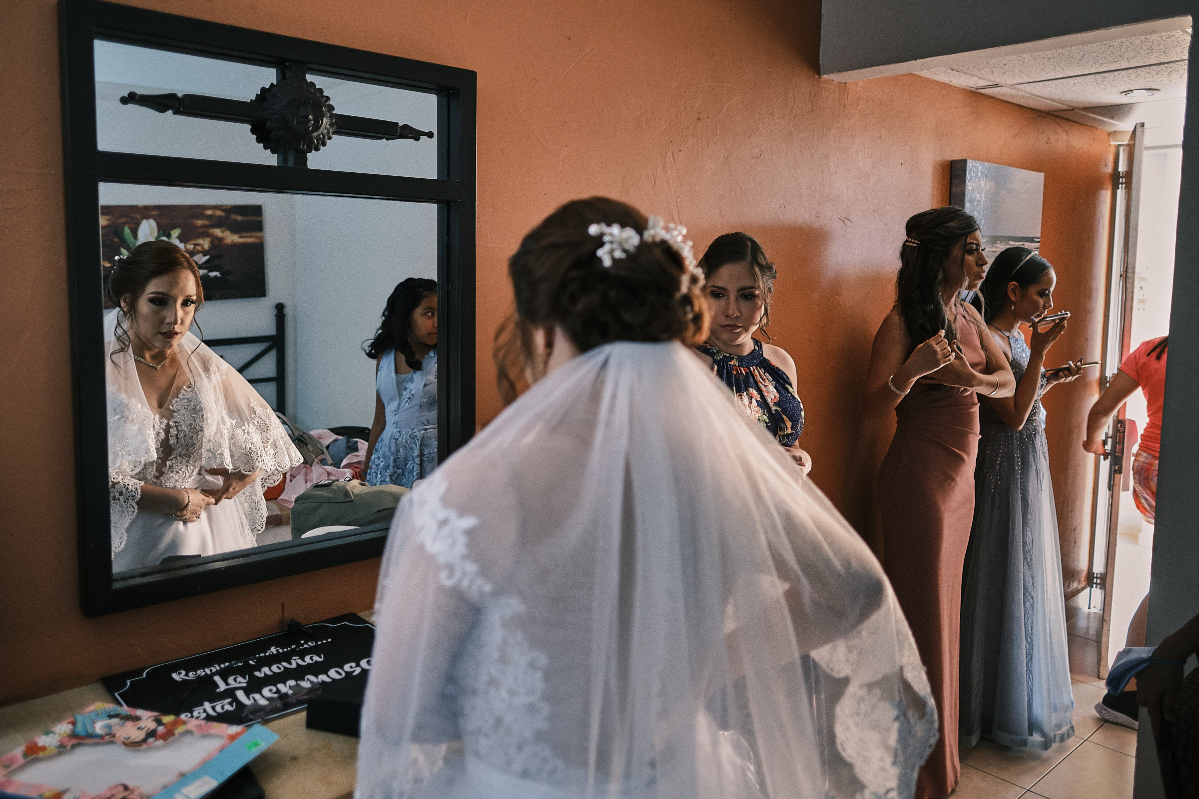 someone walks out the room as the bride is getting the last touches on her dress