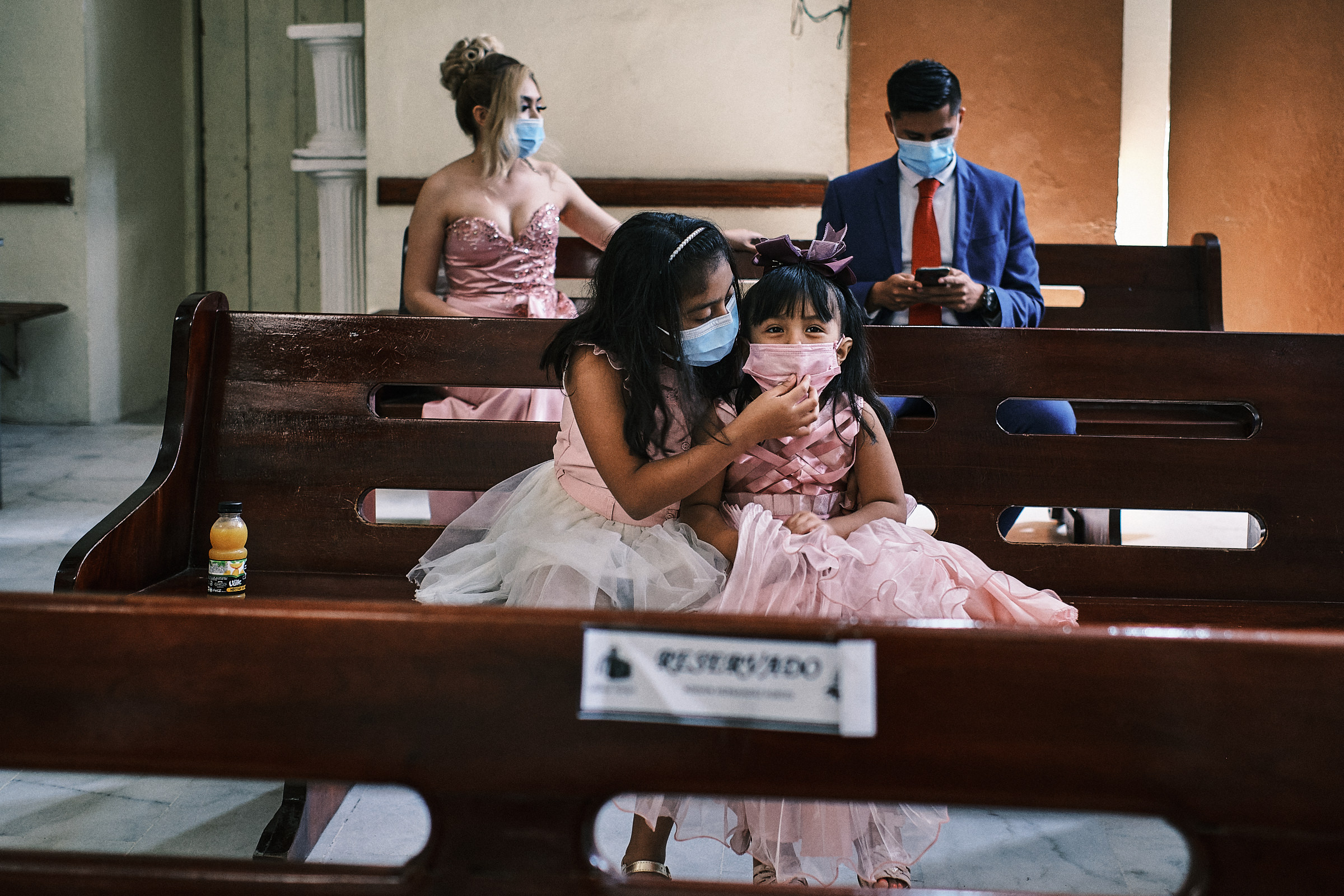 two girls play with their mask as a couple is behind and they wait for the ceremony
