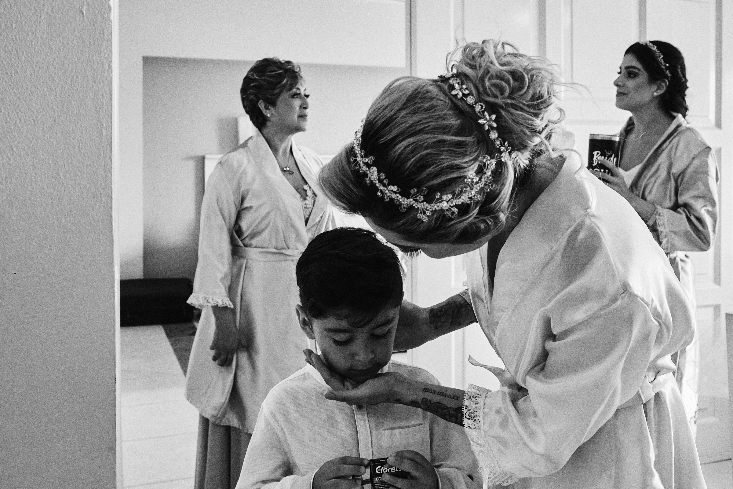 Black And White Photo Of Bride And Her Child With Mom And Bridesmaid In Background Getting Ready