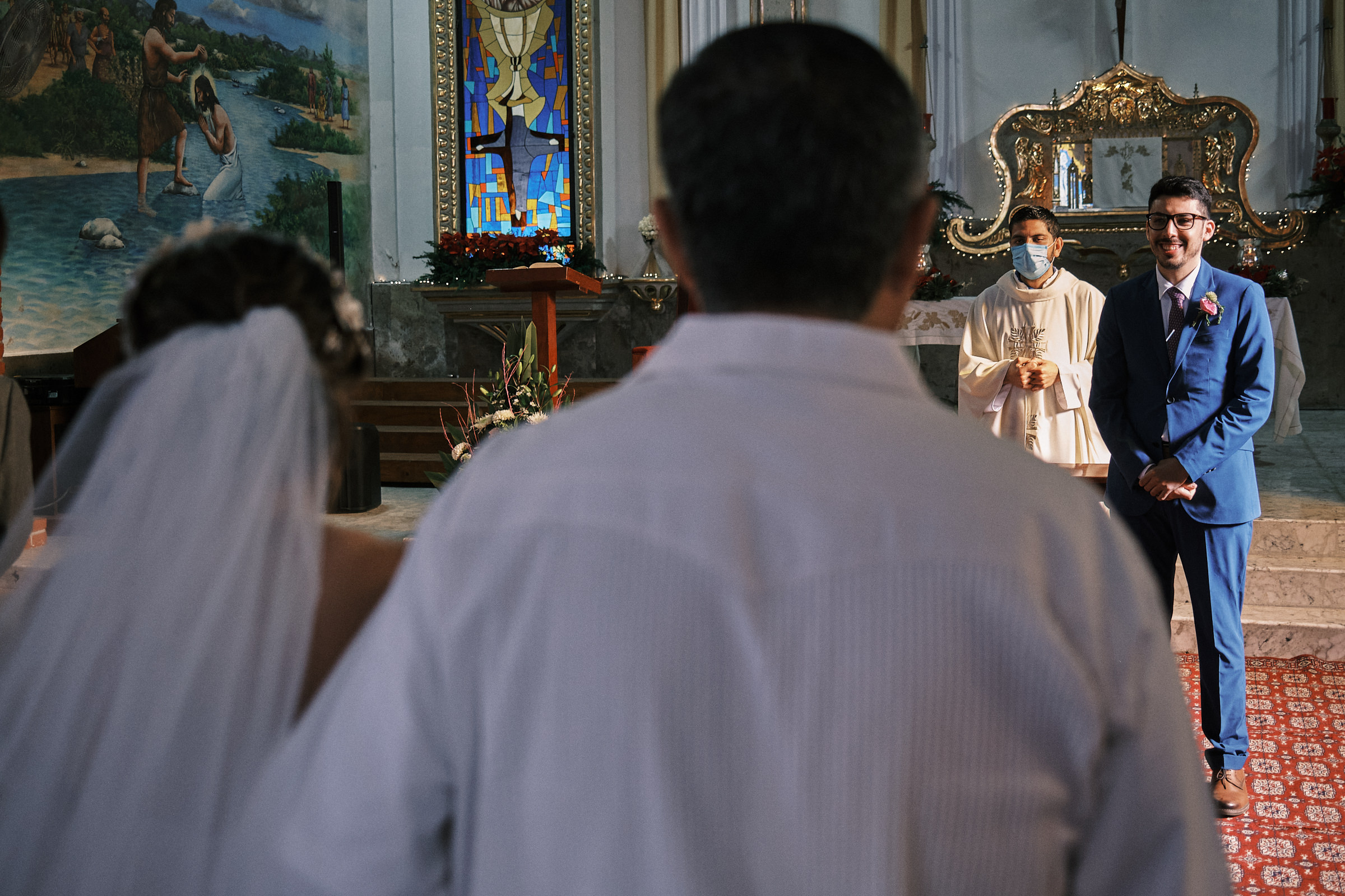 Groom Awaits For The Bride And Looks At Her As She Walks The Aisle In Catholic Ceremony