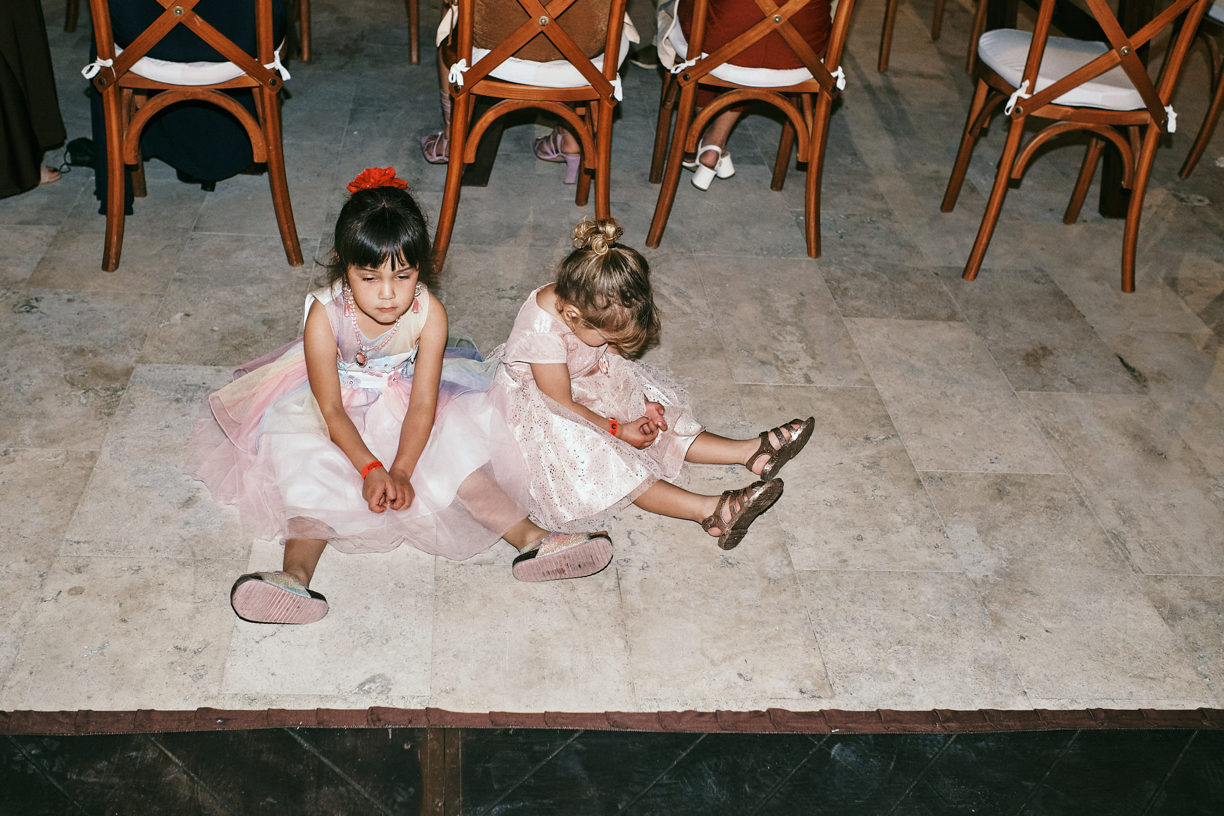Two Girls Sit Bored On The Floor At Wedding Reception In Destination Wedding In Puerto Vallarta