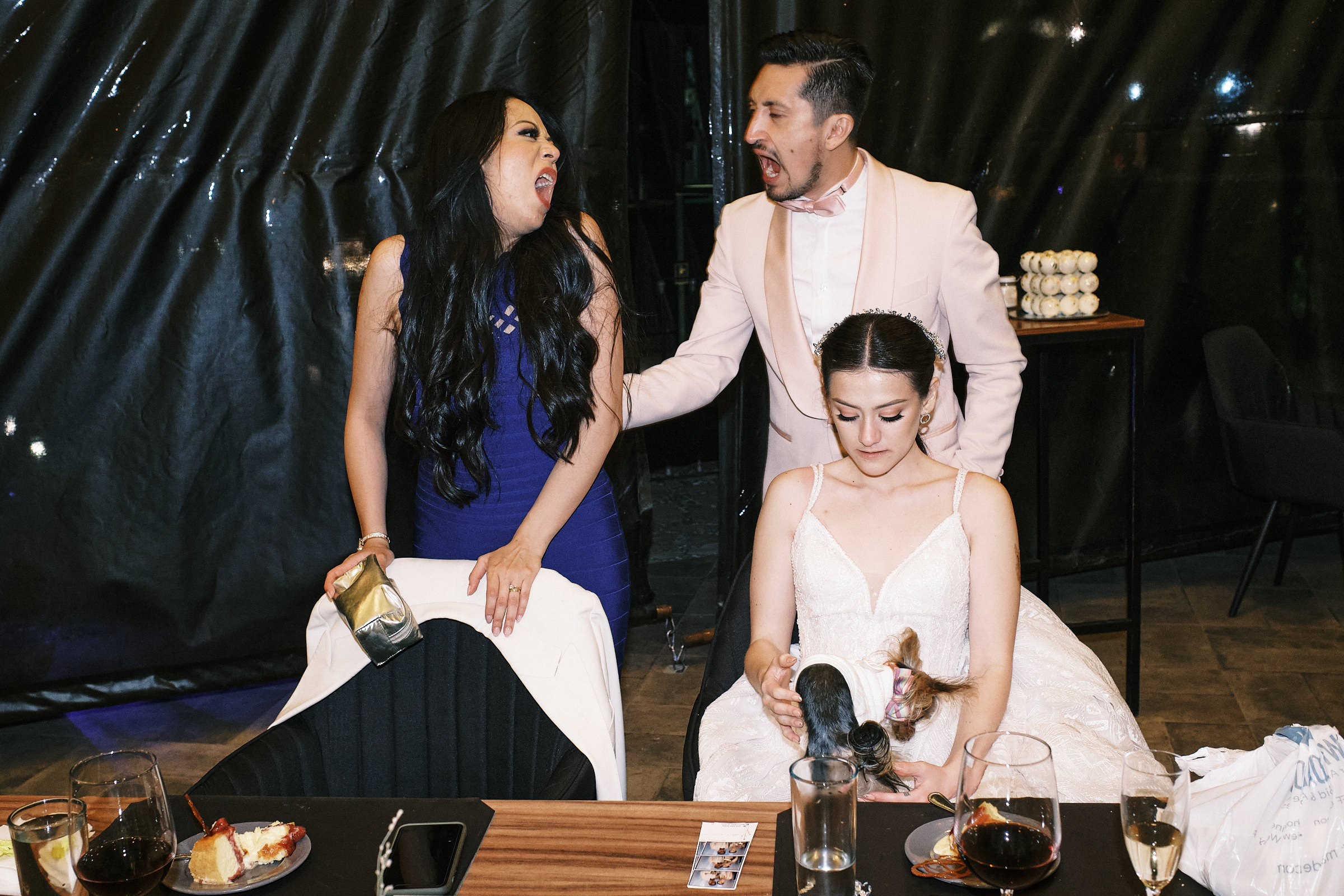 Wedding Guests Opening Their Mouth In Sync Behind Bride At Reception